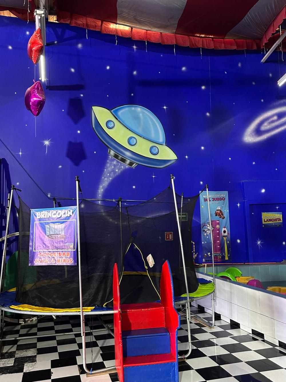 Área de juegos con mural de ovni y alienígena
