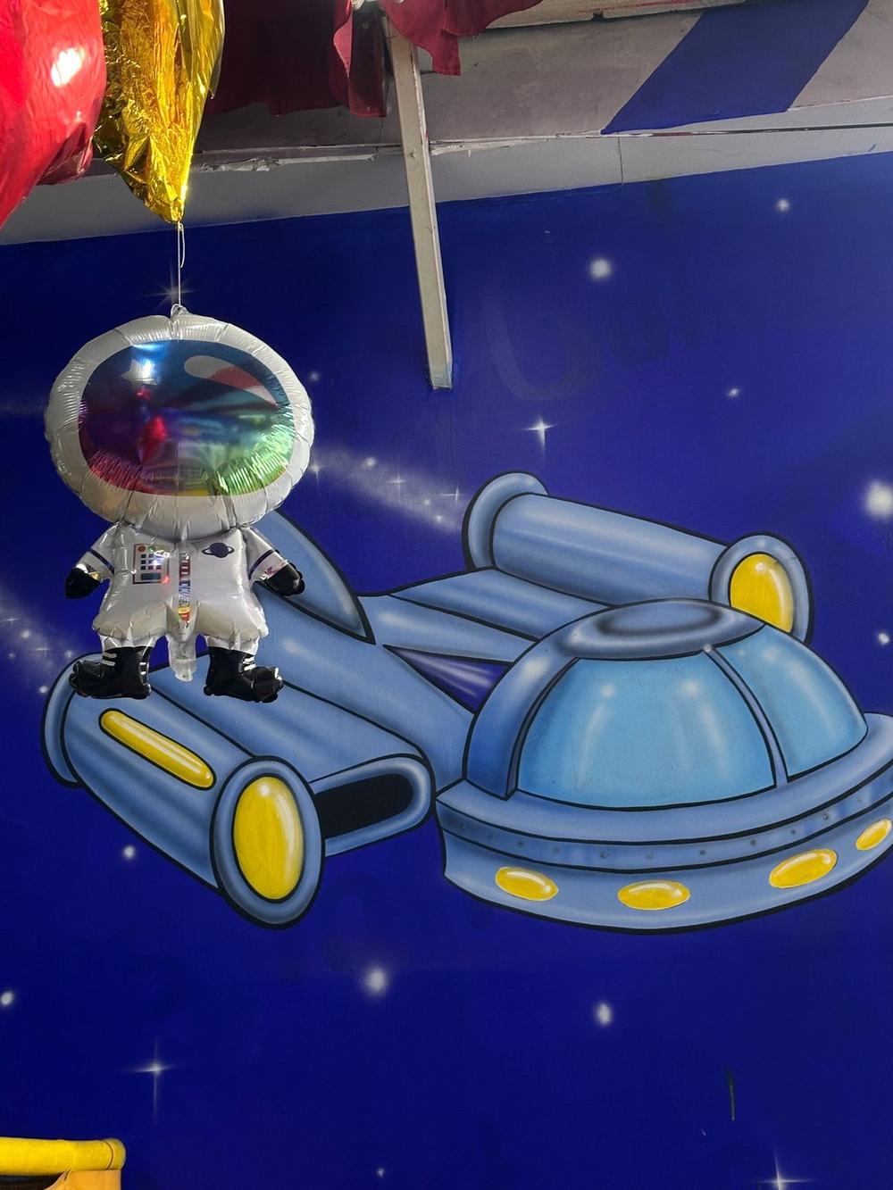 Inflable gigante de astronauta y nave espacial sobre pared estrellada